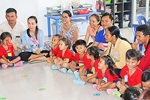 JPA Image Gallery - Preschool student with parents sitting on the floor - Jay Pritzker Academy, Siem Reap, Cambodia