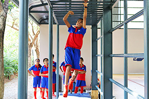 JPA Image Gallery - A student makes his way across the monkey bars during PE class - Jay Pritzker Academy, Siem Reap, Cambodia