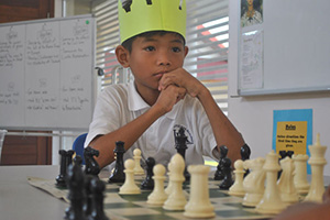 JPA Image Gallery - A primary student waits his turn at a chess game - Jay Pritzker Academy, Siem Reap, Cambodia