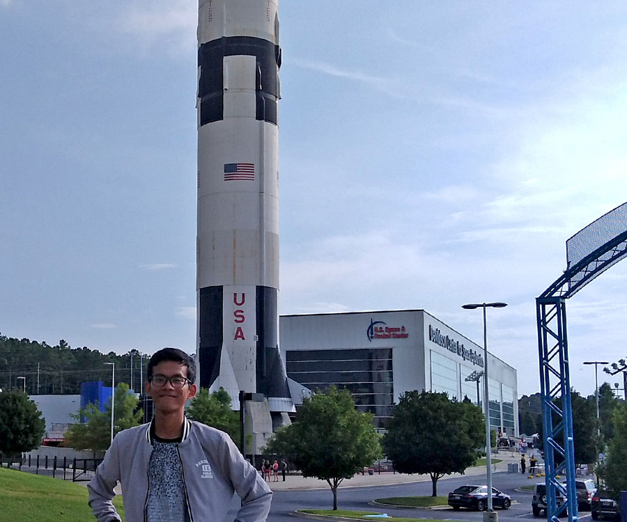 JPA student Savong ’18 with the Saturn V Rocket at the US Space and Rocket Center at Huntsville, Alabama. Jay Pritzker Academy, Siem Reap, Cambodia. Jay-Pritzker-Academy-Siem-Reap-Cambodia